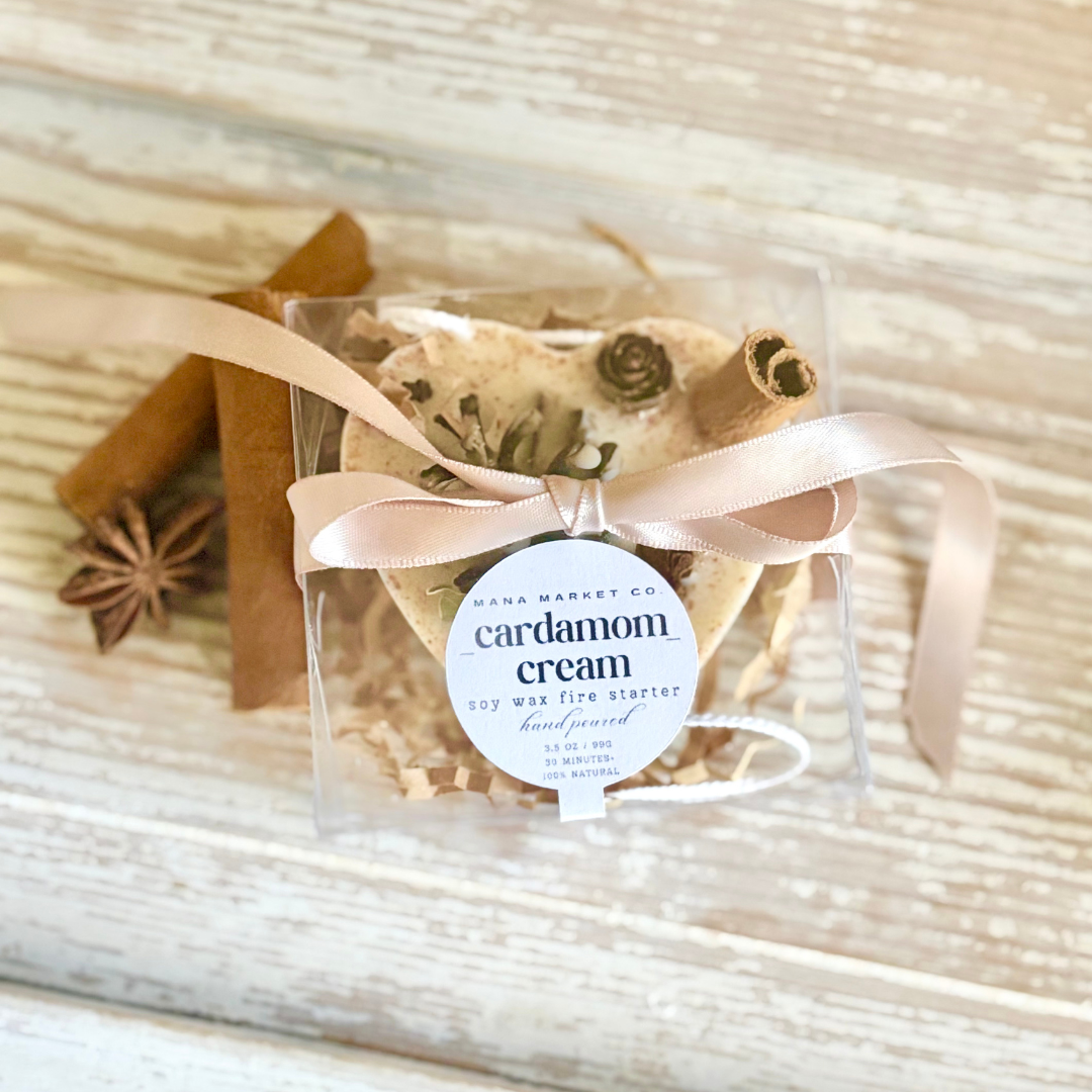 Packaged cardamom cream fire starter with a ribbon on a wooden surface
